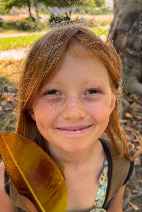 Joyaa smiling with a large autumn leaf