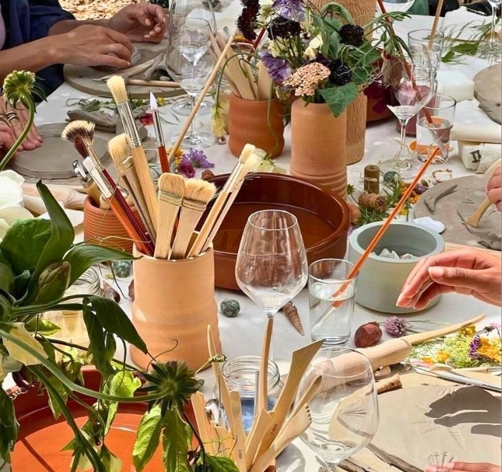 Hands messy with terracotta clay working a pottery wheel outdoors