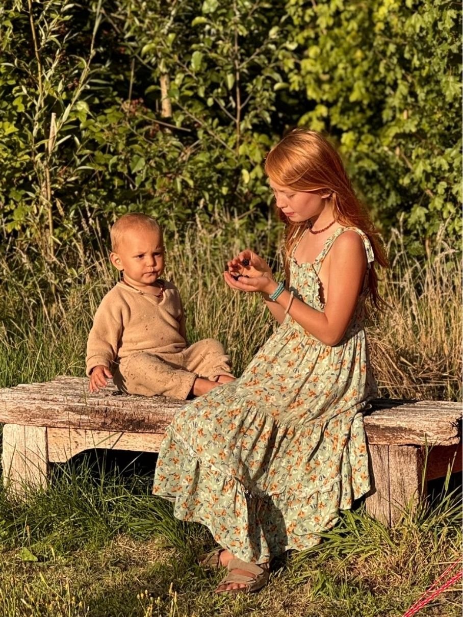 Children in linen clothes playing among ancient cork oak trees in dappled sunlight